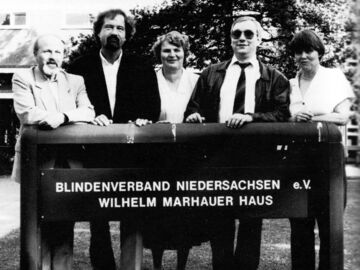 Das Foto zeigt das neue gemeinsame neue Schild des Blindenverbandes e. V. und des Wilhelm-Marhauer-Hauses, in der Kühnsstraße 18, mit Justiziarin Sigrid Wichmann, BVN-Geschäftsführer Hans-Werner Lange und Gästen (v.r.n.l.)