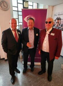 Drei Männer stehen nebeneinander. Sie sind alle festlich gekleidet. In der Mitte steht der Sozialminister Niedersachsen.